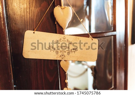 Entrance door decoration. Textile hearts and welcome label with drawn ornaments hanging on wooden doors.