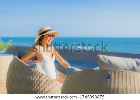 Portrait beautiful young asian woman happy smile relax sit on chair around sea ocean and outdoor swimming pool in resort hotel