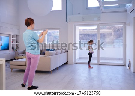 family at home little girl have online ballet training while mother is photographing her with smartphone