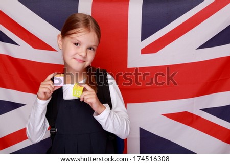 Studio image of a charming young schoolgirl holding cubes with letters of the alphabet on the background of the flag UK