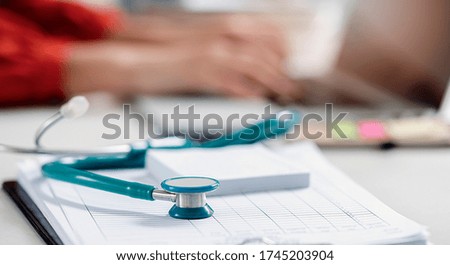 Closeup green stethoscope on doctor table with blur background doctor hand using laptop.
