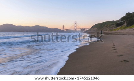 A man jogging towards the Golden Gate Bridge as the sun sets in San Francisco.