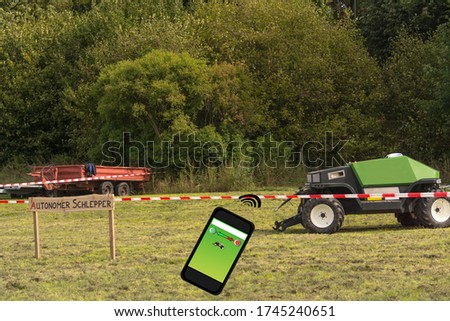 Autonomous tractor in the field. Wooden sign with inscription in German autonomous tractor. Smart farming and digital transformation in agriculture.