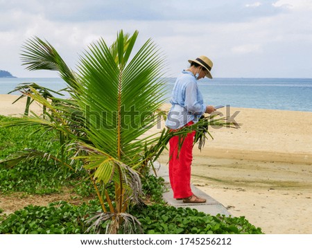 Woman on Karon beach taking pictures using tablet, Phuket, Thailand