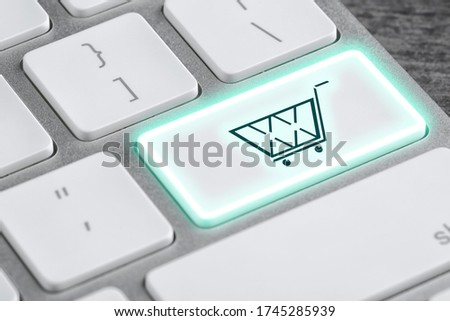 Modern computer keyboard with cart symbol on table, closeup view. Internet shopping