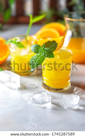 Fresh orange juice, orange slices, mint leaves and ice on a wooden table. Selective focus, copy space