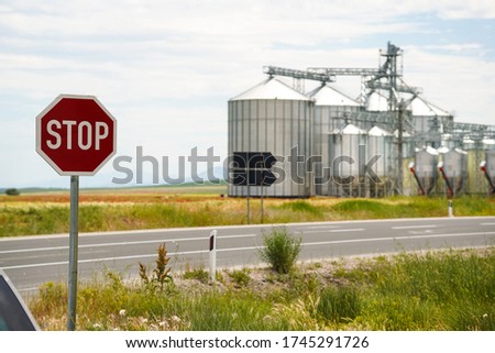 Agricultural Silos, Storage and drying of grains. Stop sign. Wheat, corn, soy, sunflower against the blue sky with rice fields.