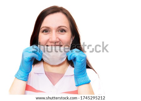 A young woman in blue medical gloves takes off her protective mask and smiles. A confident girl, a female doctor in a medical mask.Protection against covid-19 coronavirus.