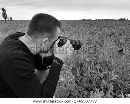 attractive man taking photos in poppy field