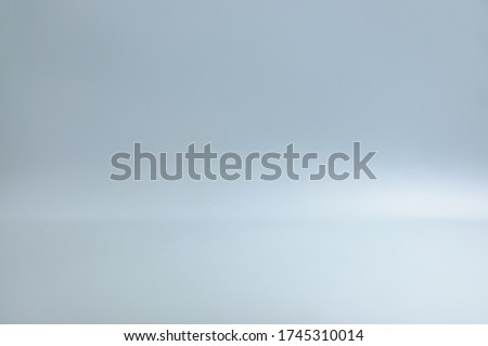 Blurred blank grey gradient background for product display. Grey backdrop on floor in empty studio room with dim light.