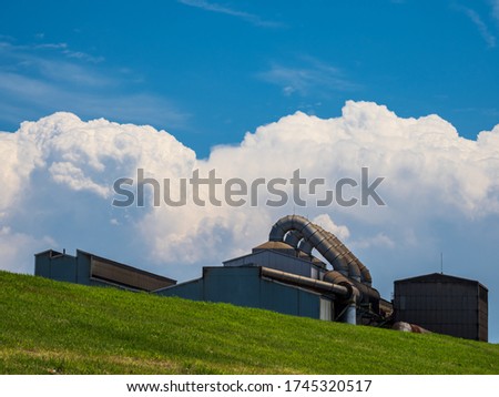 Summer clouds and a factory on a hill.