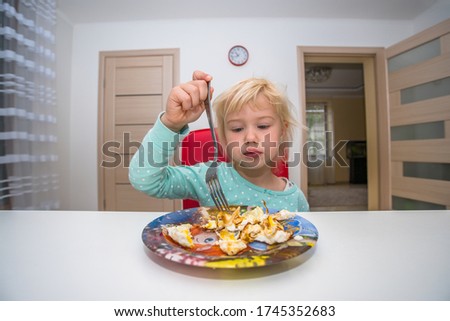 little blonde girl eating breakfast at home in the kitchen omelet no appetite. beautiful baby. homemade food.