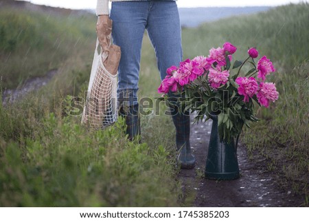 a girl with a bouquet of flowers and a string bag with baguettes. spring mood in the village.
