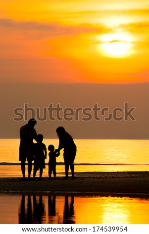 Silhouette of family on the beach during sunset.
