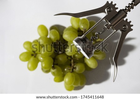 green grapes, cork and corkscrew on a white background; studio photography with soft light