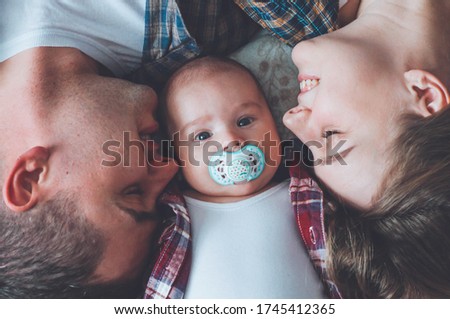 portrait of father and mother with three month old son. kissing little son. happy young family. quarantine in the family circle