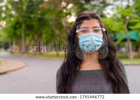 Face of young Indian woman wearing mask and face shield at the park outdoors Royalty-Free Stock Photo #1745446772