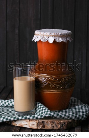 Homemade baked milk in a jug and in a clear glass on an old wooden background. Rustic. Milk products. Background image, copy space