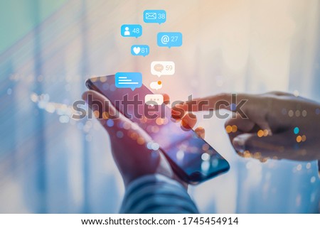 Woman hand using a social media marketing concept on mobile phone with notification icons of like, message, comment and star above mobile phone screen. Royalty-Free Stock Photo #1745454914