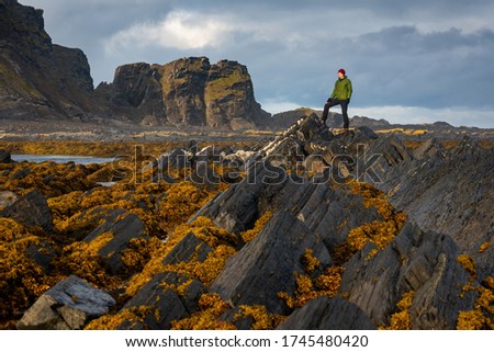 A man stands on a stone and looks into the distance