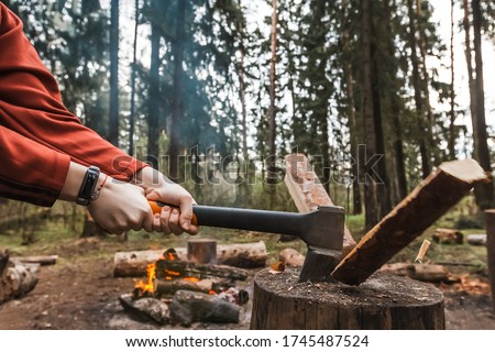 Female strong hands chop firewood with axe for bonfire. Powerful ax blow. Survival on camping trip. Harvesting wood in forest. Camp wild tourists. Splitting logs with sharp hatchet. Young woodcutter Royalty-Free Stock Photo #1745487524
