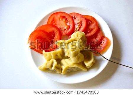Ripe tomatoes sliced and meat dumplings with a fork