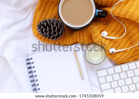 Coffee, clean notebook. keyboard, cone , candle, earpods on white crumpled sheets and yellow knitted cover top view. Woman working home. Cozy breakfast. Mockup. Flat lay style.
