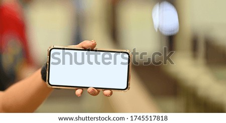 Cropped image of woman holding a white blank screen smartphone in horizontal. Hands holding mobile with empty screen for advertisement concept.