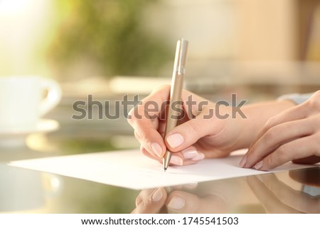 Close up of woman hand writing on a paper on a desk at home Royalty-Free Stock Photo #1745541503