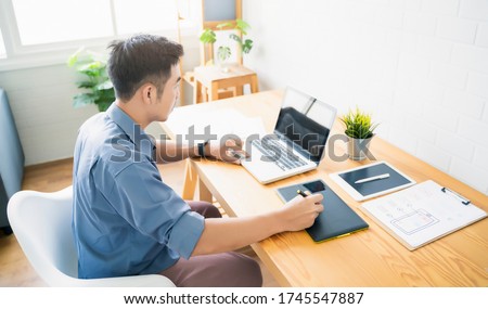 Working from home web designing graphical user interface UX UI, home office using computer laptop and pen sketching graphics tablet device creative planning innovative ideas, asian man quarantine 