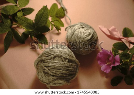 Ball of gray thread or yarn on the pink background with rose and leafs. Girly backdrop. Bow.