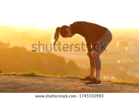 Side view portrait of a tired runner resting after exercise in city outskirts at sunset Royalty-Free Stock Photo #1745550983