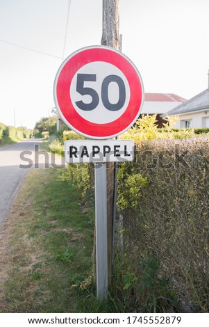 Round 50 kilometers per hour speed limit road sign in town. Written in french "Rappel", it is a reminder. Vertical shot.