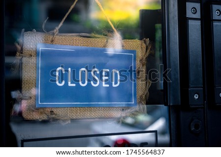 
The blue symbol on the brown sackcloth shows the words closing the shop hanging on the glass front door. Because covid-19 in the evening with the sunset light, symbolic concept