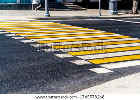 Striped yellow and white pedestrian zebra crossing on gray asphalt, abstract background. Crosswalk on the road for people's safety
