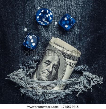 Hundred dollar bill and dice in torn jeans hole