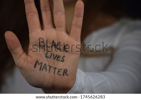 Black Lives Matter written on long haired white woman's hand. Caucasian girl  against racism and police brutality. Support to African Americans. Royalty-Free Stock Photo #1745626283