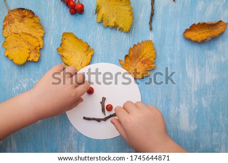 little child making autumn decoration from leaves and forest berries. Children's art project. DIY concept. Step-by-step photo instruction.