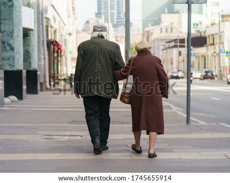 Photography of pair of aged man and woman. Backs, rear view. Pensioners go for a walk. Quarantine time is finished. Coronavirus pandemic lifestyle of old people. Royalty-Free Stock Photo #1745655914
