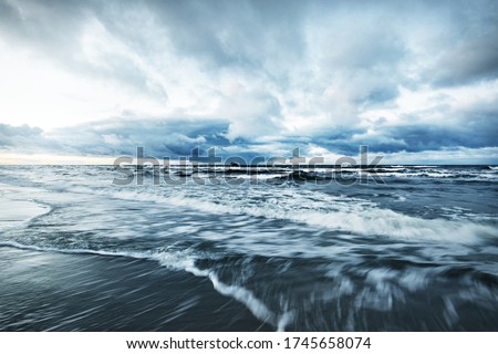 Storm clouds above the Baltic sea in winter, long exposure. Dramatic sunset sky, waves and water splashes. Dark seascape. Germany Royalty-Free Stock Photo #1745658074