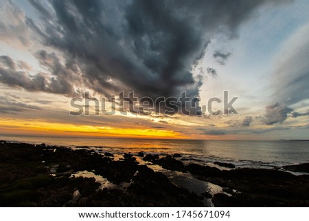 STORM CLOUD APPROACHING THE BEACH AT SUNSET AT SEA Royalty-Free Stock Photo #1745671094