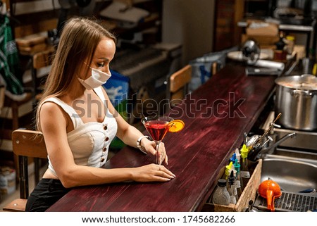 girls in medical masks drink cocktails.  girl in a medical mask is resting in a pub. girl in a medical mask in a pub