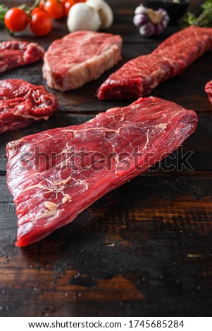 Alternative Flank bavette or flap steak beef t steak near tri-tip and top blade oyster cuts close up in front of other cuts in butchery on old wood table side view vertical Royalty-Free Stock Photo #1745685284