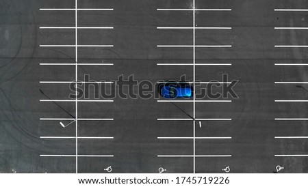 Top view on an empty parking lots with one blue car. Aerial view of car park. Royalty-Free Stock Photo #1745719226