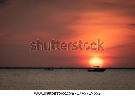 Dreamy Sunset with the un at the horizon and a boat in front