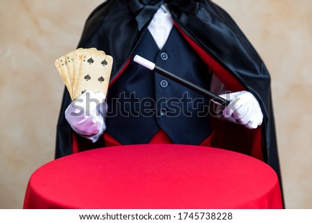 Illusionist holding magic wand and playing card. Imagination and magic concept
