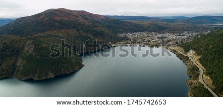 Panorama Aerial View of the forest, Lake Lacar and San Martin de los Andes village in the Andes mountains, Patagonia Argentina, in autumn