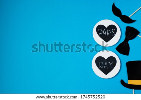 Happy father's day. On a blue background - a black mustache, bow tie, bowler hat and the inscription dad's day. Copy space.