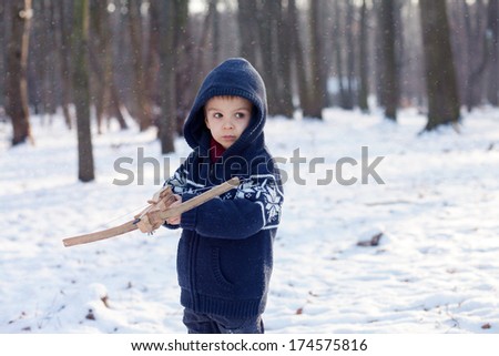 Little boy, playing with crossbow in the park