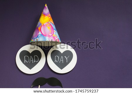 Happy father's day. On a purple background - black mustache, festive cap, two hearts with the inscription daddy's dayCopy space.